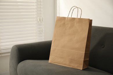 Photo of Paper bag on grey sofa indoors. Space for text