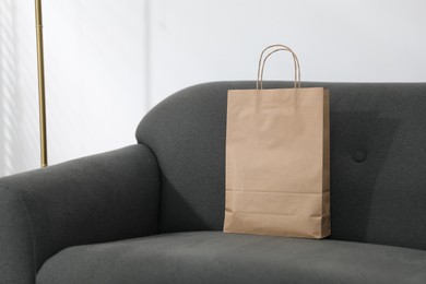 Photo of Paper bag on grey sofa indoors. Space for text