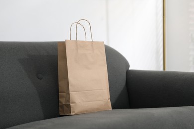 Photo of Paper bag on grey sofa indoors. Space for text