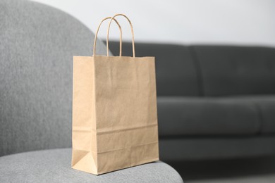 Photo of Paper bag on grey armchair indoors, closeup. Space for text