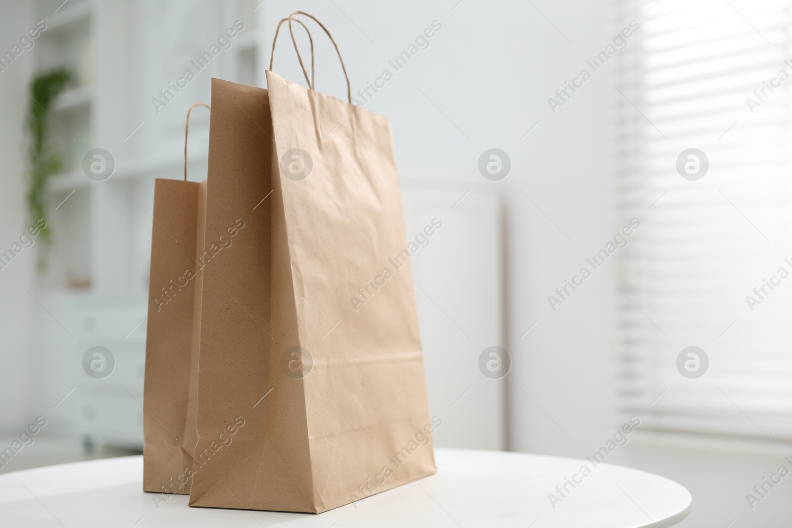 Photo of Paper bags on white table indoors. Space for text