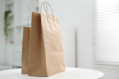 Photo of Paper bags on white table indoors. Space for text