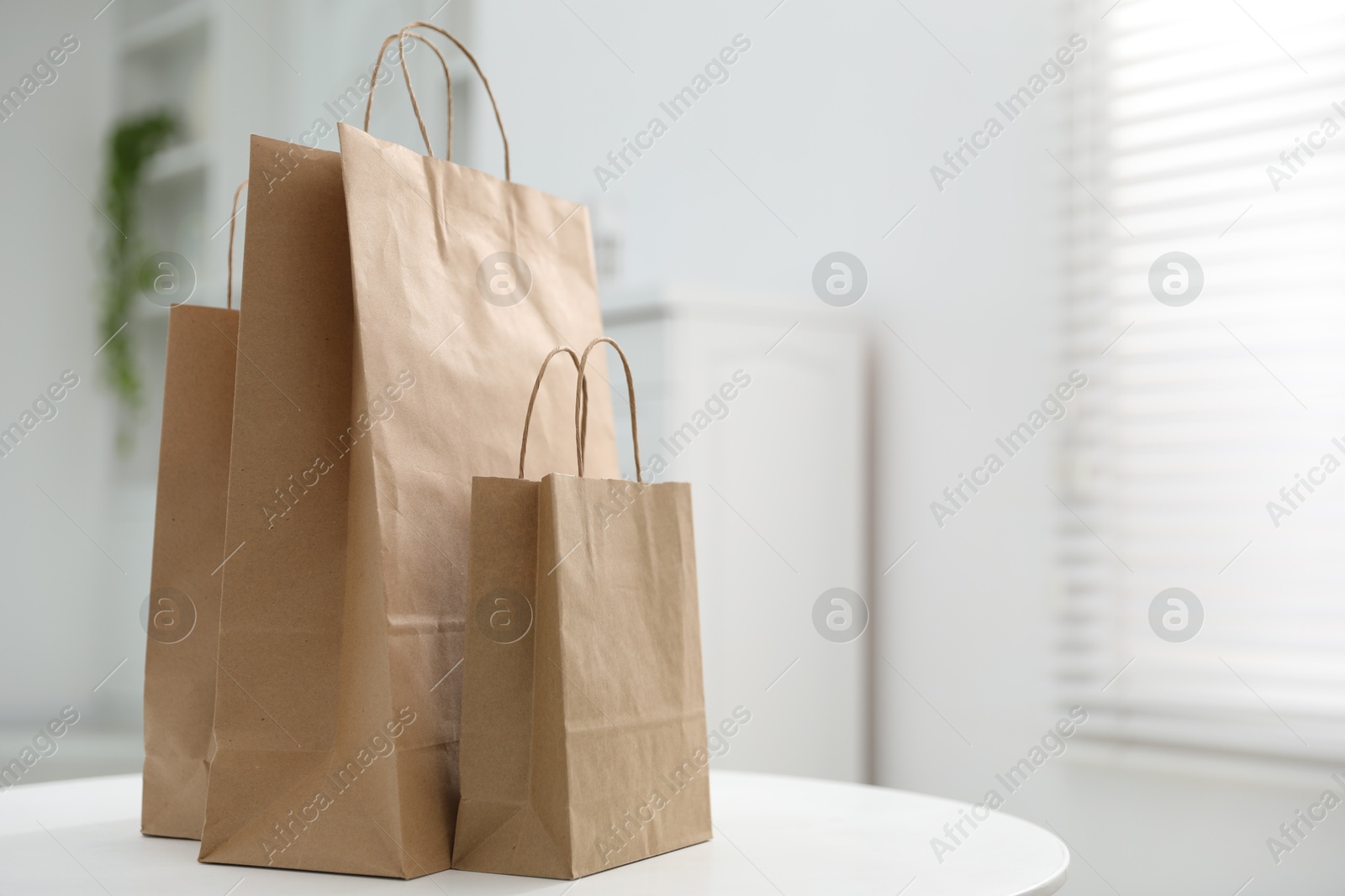 Photo of Paper bags on white table indoors. Space for text