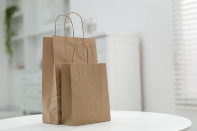 Photo of Paper bags on white table indoors. Space for text