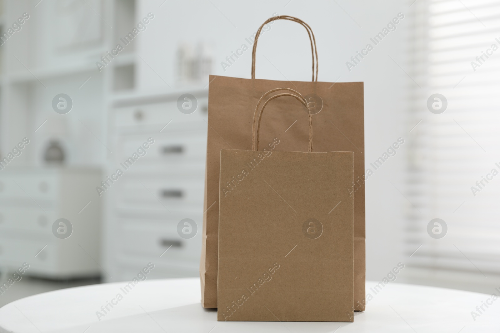 Photo of Paper bags on white table indoors. Space for text