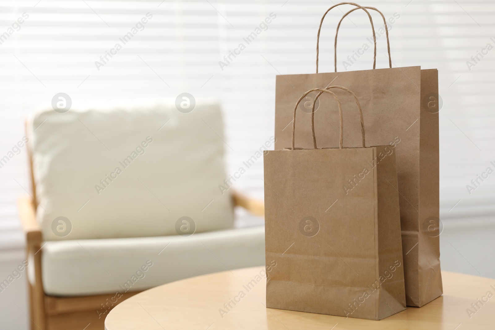 Photo of Paper bags on wooden table indoors, closeup. Space for text