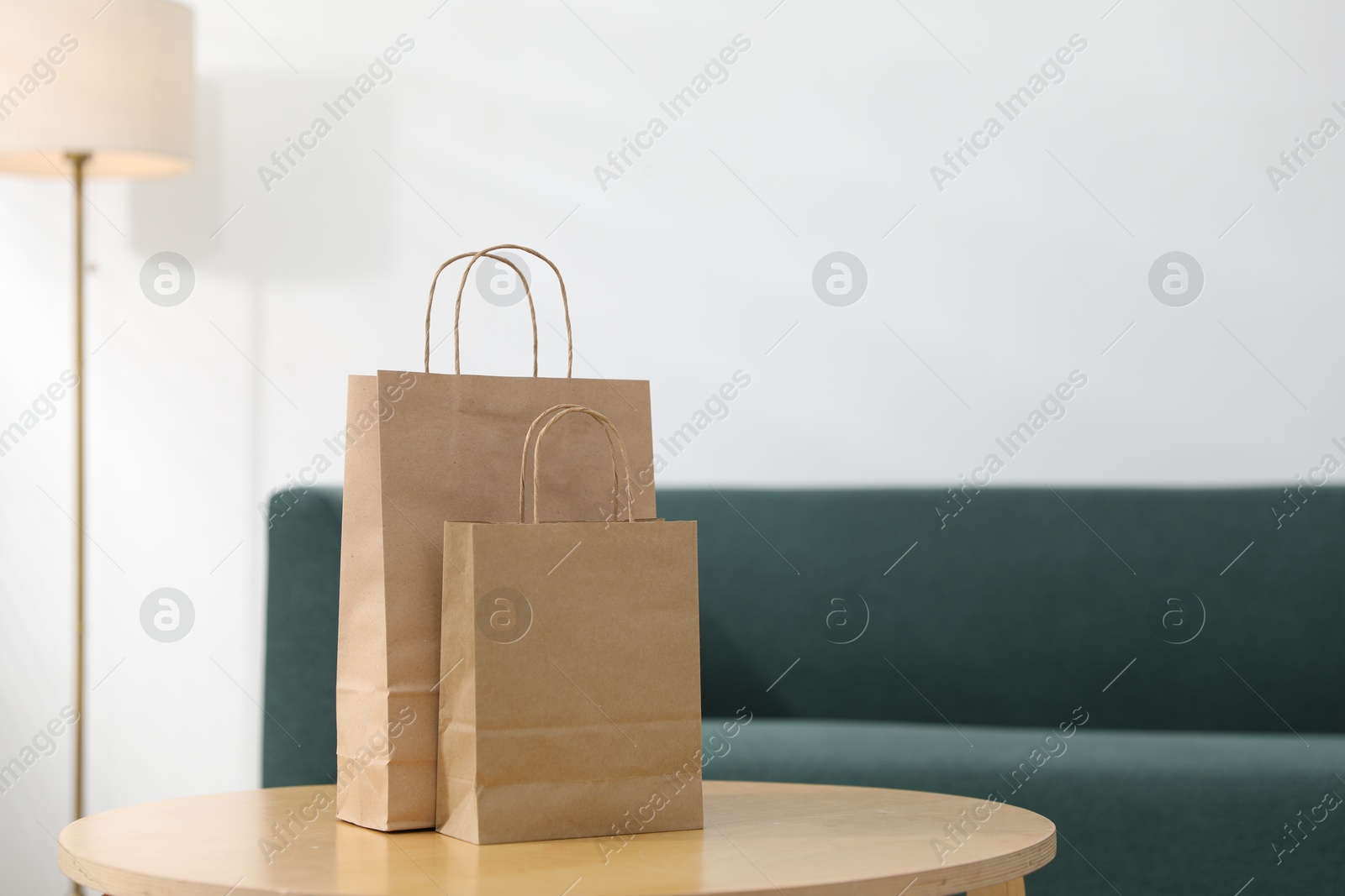 Photo of Paper bags on wooden table indoors, closeup. Space for text