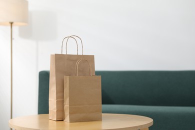 Photo of Paper bags on wooden table indoors, closeup. Space for text