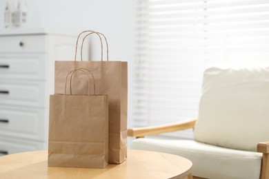 Photo of Paper bags on wooden table indoors, closeup. Space for text