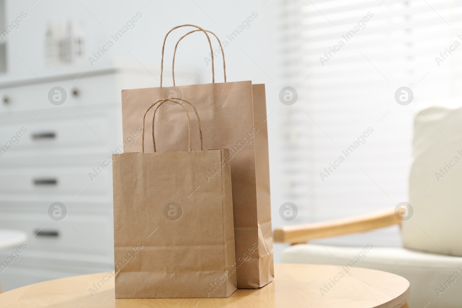 Photo of Paper bags on wooden table indoors, closeup. Space for text