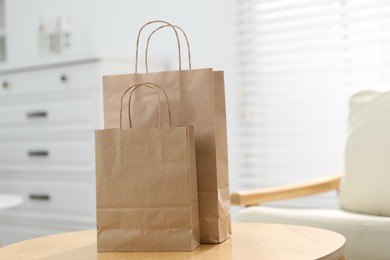 Photo of Paper bags on wooden table indoors, closeup. Space for text