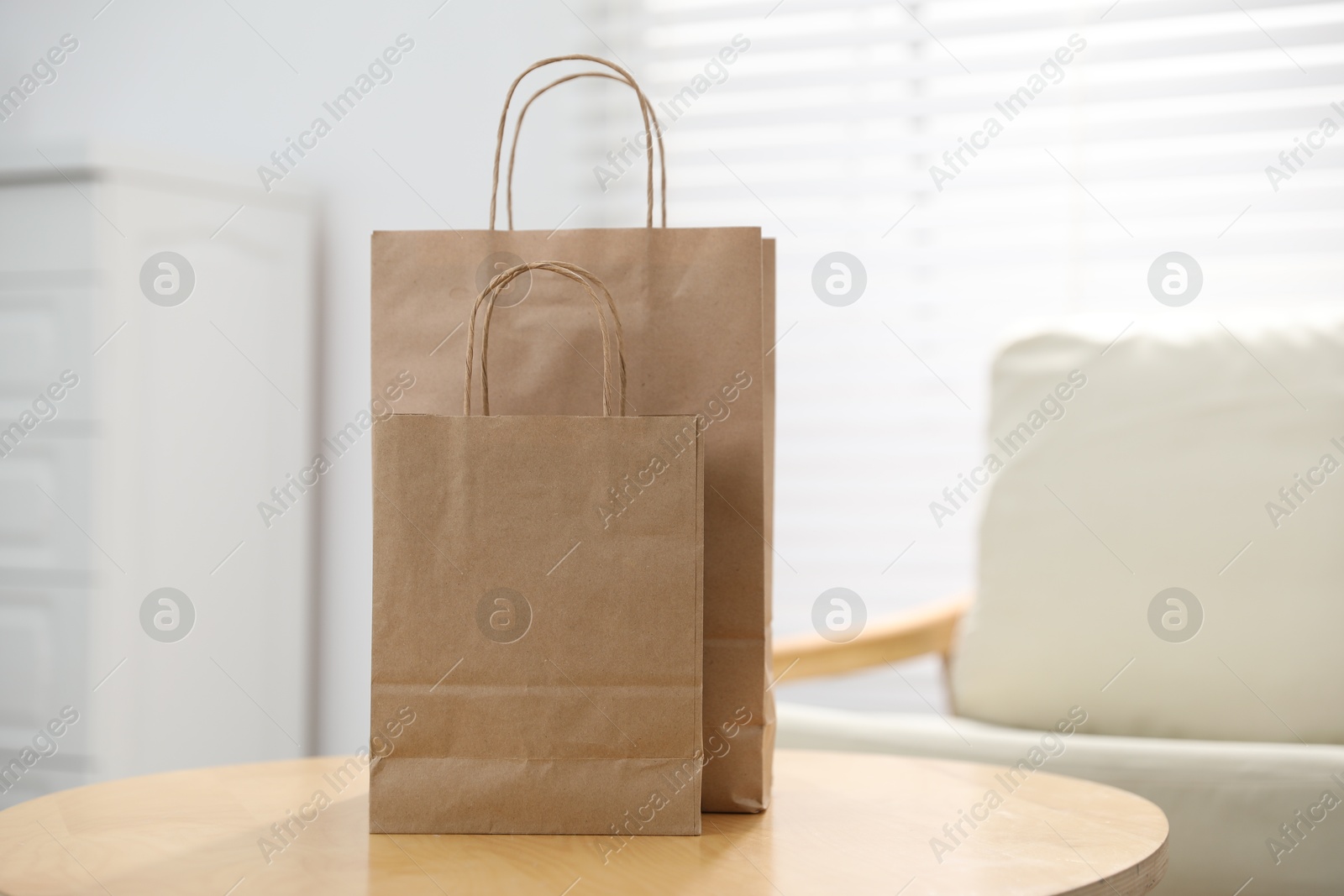 Photo of Paper bags on wooden table indoors, closeup. Space for text