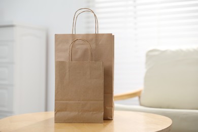 Photo of Paper bags on wooden table indoors, closeup. Space for text