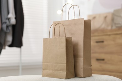 Photo of Paper bags on white pouf indoors, closeup