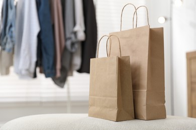 Photo of Paper bags on white pouf indoors, closeup. Space for text