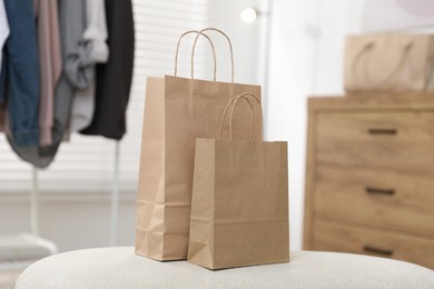 Photo of Paper bags on white pouf indoors, closeup