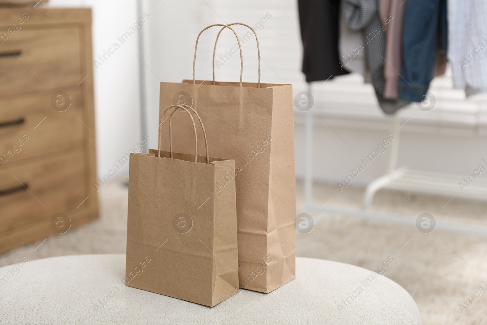 Photo of Paper bags on white pouf indoors, closeup