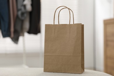 Photo of Paper bag on white pouf indoors, closeup. Space for text