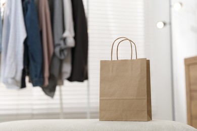 Photo of Paper bag on white pouf indoors. Space for text
