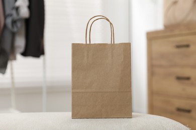 Photo of Paper bag on white pouf indoors, closeup