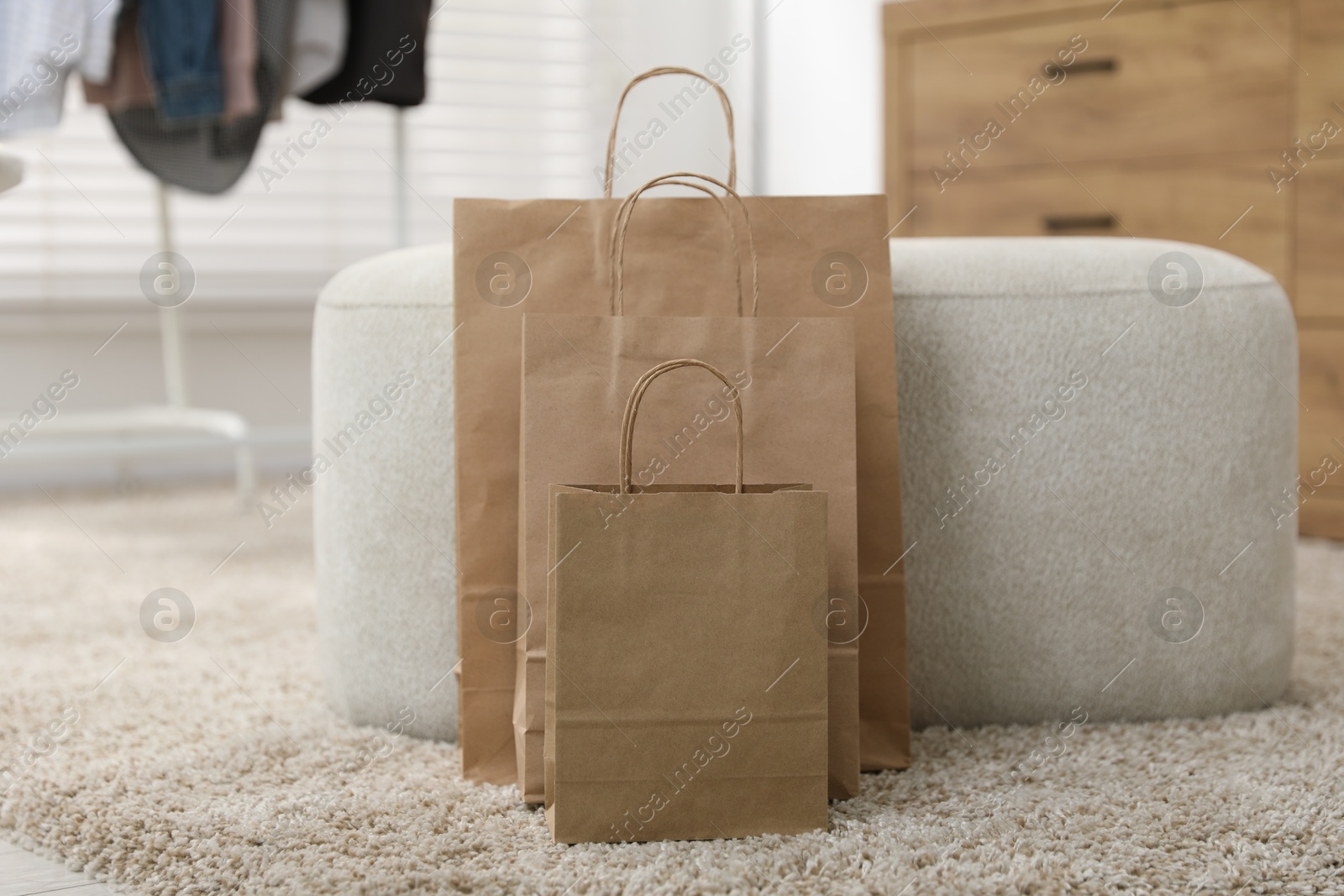 Photo of Paper bags near pouf on carpet indoors, closeup