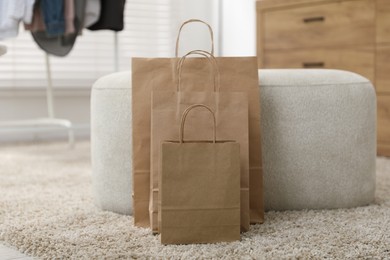 Photo of Paper bags near pouf on carpet indoors, closeup