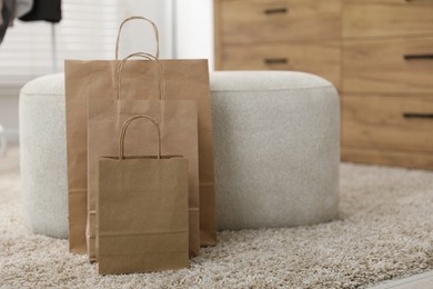 Photo of Paper bags near pouf on carpet indoors, closeup. Space for text