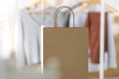 Photo of Paper bag in front of clothing rack indoors, closeup