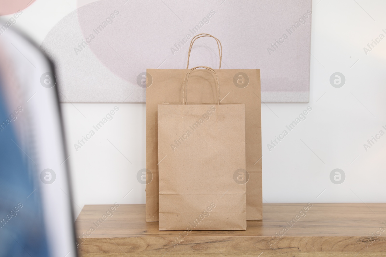 Photo of Paper bags on wooden chest of drawers near white wall indoors