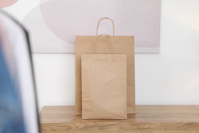 Photo of Paper bags on wooden chest of drawers near white wall indoors