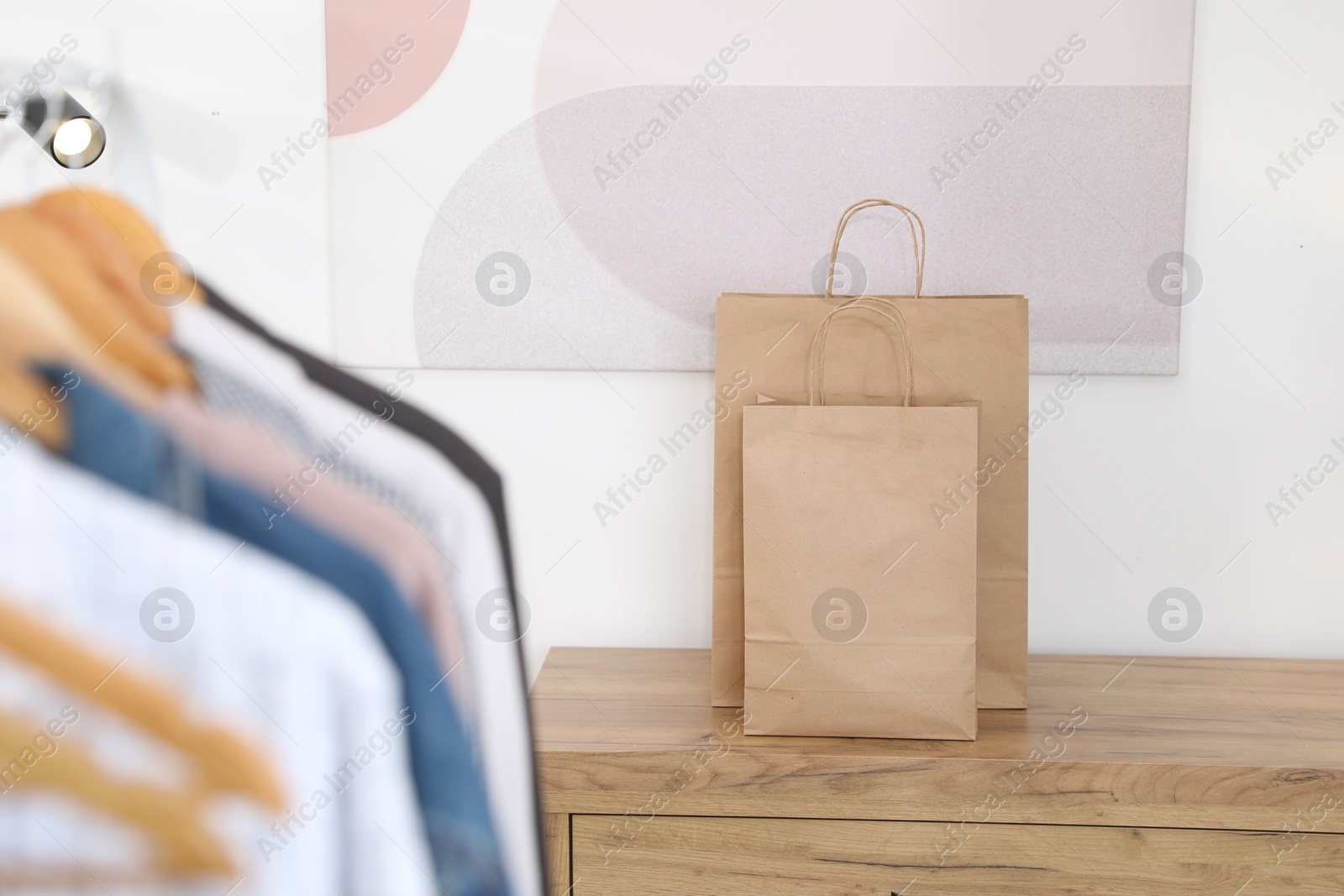 Photo of Paper bags on wooden chest of drawers near white wall indoors