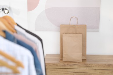 Photo of Paper bags on wooden chest of drawers near white wall indoors