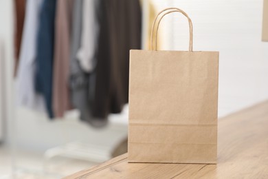 Photo of Paper bag on wooden counter indoors, closeup. Space for text