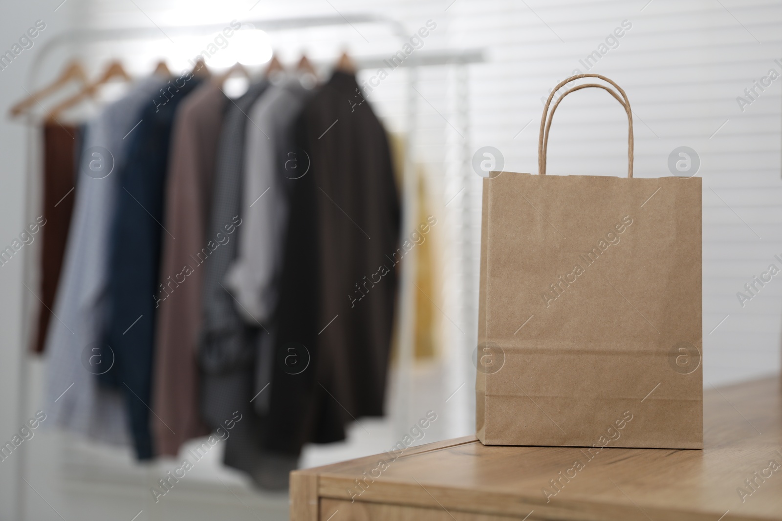 Photo of Paper bag on wooden chest of drawers indoors, closeup. Space for text