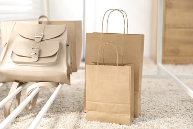 Photo of Paper bags near backpack on carpet indoors, closeup