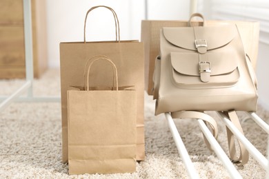 Photo of Paper bags near backpack on carpet indoors, closeup