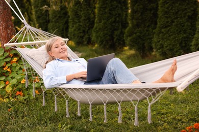 Photo of Senior woman with laptop in hammock outdoors