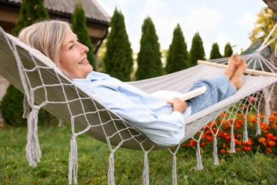 Photo of Senior woman with book in hammock outdoors