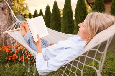 Photo of Senior woman reading book in hammock outdoors