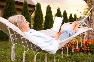 Photo of Senior woman reading book in hammock outdoors