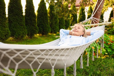 Photo of Senior woman resting in comfortable hammock outdoors