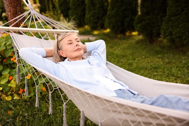Photo of Senior woman resting in comfortable hammock outdoors