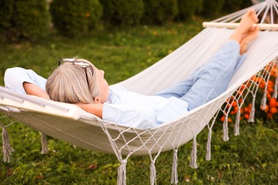 Photo of Senior woman resting in comfortable hammock outdoors