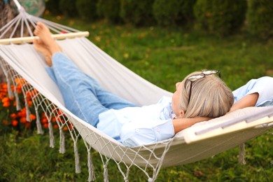 Photo of Senior woman resting in comfortable hammock outdoors