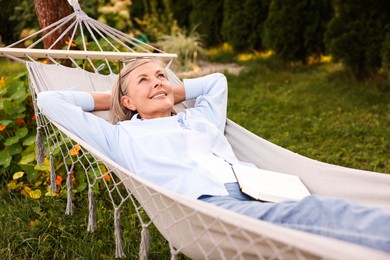 Photo of Senior woman with book resting in hammock outdoors
