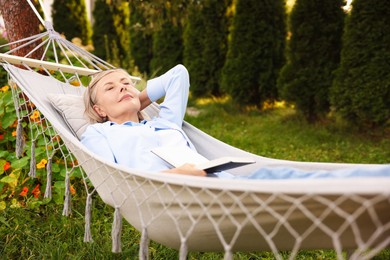 Photo of Senior woman with book resting in hammock outdoors