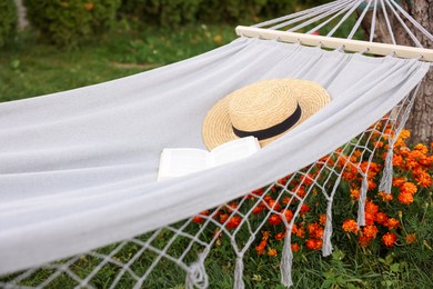 Photo of Straw hat and book on hammock outdoors