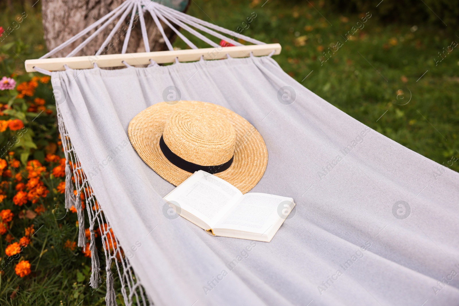 Photo of Straw hat and book on hammock outdoors