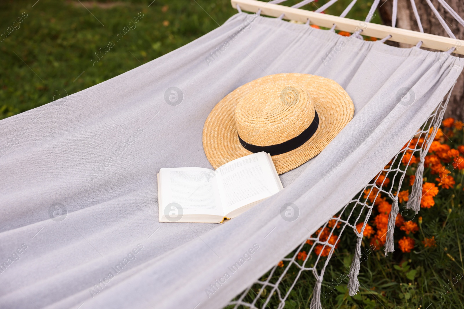 Photo of Straw hat and book on hammock outdoors