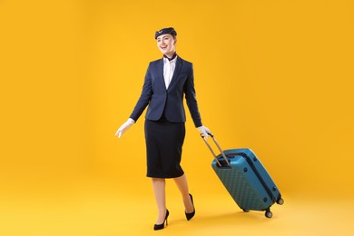 Photo of Positive stewardess with suitcase on yellow background